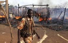 A policeman walks past the smouldering remains of a market in Rubkona near Bentiu in South Sudan, April 23, 2012.