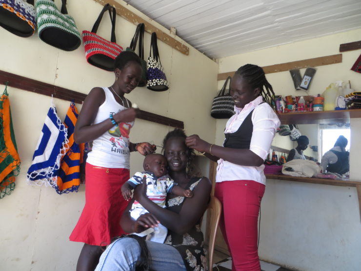 Deborah, far right, does hair in her shop where she and her sister make bags and other wares.